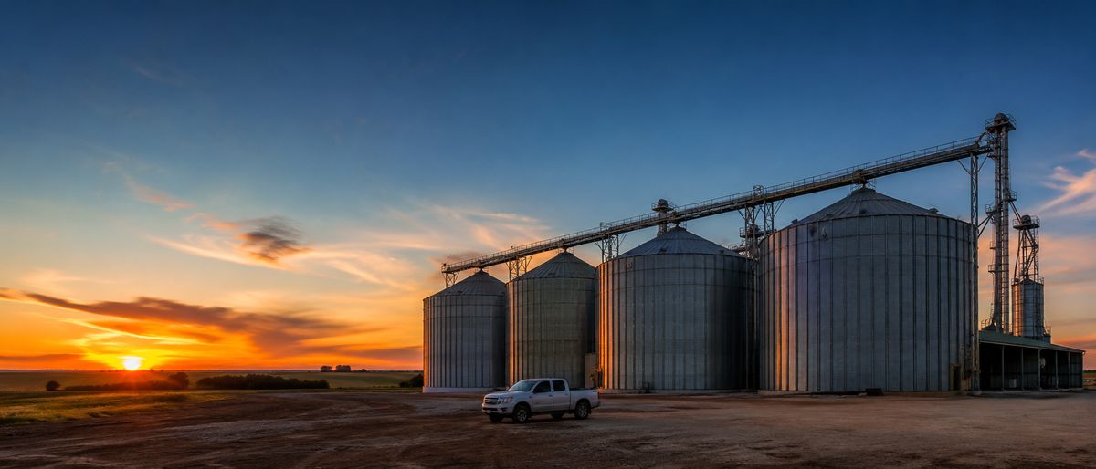 Conjunto de silos metálicos ao pôr do sol